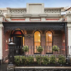 an old brick house with wrought iron fence