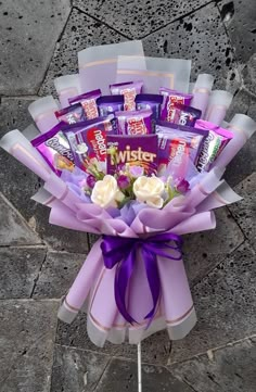 a bouquet of chocolates and roses on a stick with purple ribbon tied around it