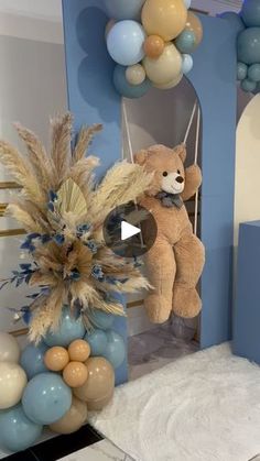 a teddy bear sitting on top of a table next to balloons