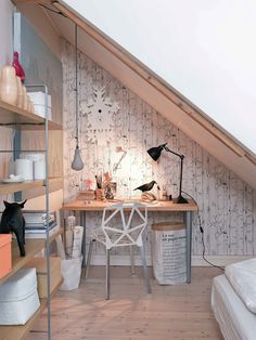 an attic bedroom with white walls and wooden flooring is furnished with shelving units