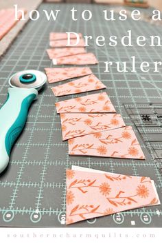 a pair of scissors sitting on top of a cutting board next to cut pieces of fabric