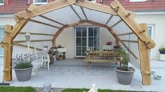 a wooden gazebo sitting on top of a patio next to potted plants and flowers