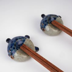 two blue and white ceramic birds with chopsticks sticking out of them'heads