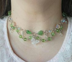 a woman wearing a green and white necklace with charms on it's neckline