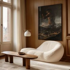 a living room with a large painting on the wall and a white chair in front of it