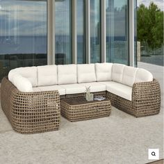 an outdoor sectional sofa with ottomans and coffee table in front of large glass windows