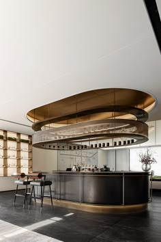 a modern kitchen with black counter tops and gold accents on the ceiling, along with bar stools