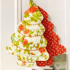 two red and green christmas tree ornaments hanging on a white doorknob with flowers