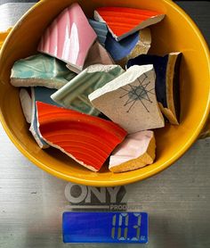 a yellow bowl filled with lots of different types of soaps on top of a scale