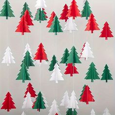 paper christmas trees hanging from strings on a wall