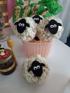 three sheep made out of rice sitting on top of a table next to a vase filled with flowers