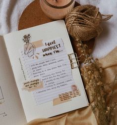 an open notebook sitting on top of a bed next to a vase and twine