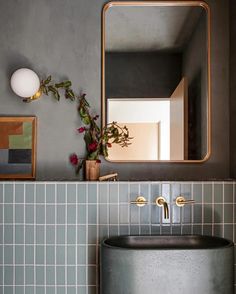 a bathroom sink sitting under a mirror next to a potted plant