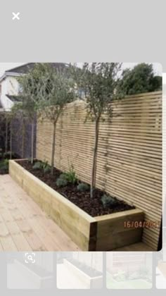 a wooden planter filled with plants on top of a wooden deck next to a fence