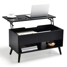 a laptop computer sitting on top of a wooden shelf next to a table with books