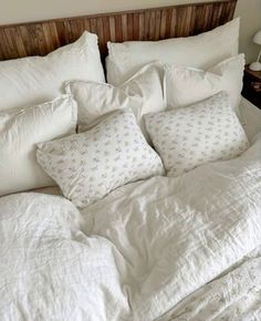 an unmade bed with white linens and pillows