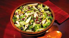 a salad with apples and cranberries in a wooden bowl on a red table