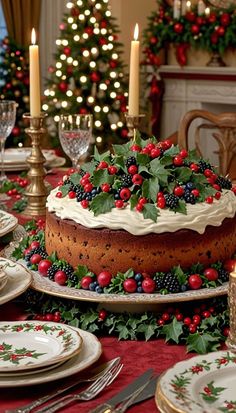 a decorated christmas cake with holly and berries on the top is surrounded by other holiday decorations