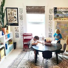 two children are sitting at a table in front of a map and bookshelf