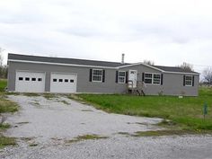 a gray house with two garages in the grass