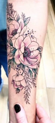 a woman's arm with flowers on it and a video player in the background