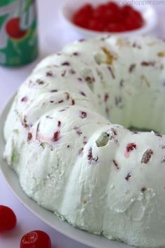 a bundt cake with white frosting and cherries on the side