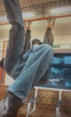 a man hanging upside down on a subway train with his feet in the air,