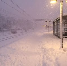 a train traveling down tracks covered in snow next to a street light and traffic signal