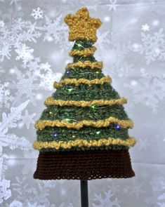 a crocheted christmas tree with lights on it's top is shown in front of snowflakes