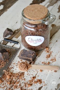 a glass jar filled with chocolate pieces next to a cookie sheet and spatula on top of a wooden table