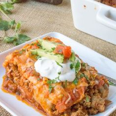 a white plate topped with lasagna covered in sour cream and garnish