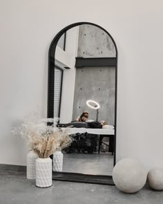 a mirror sitting on top of a table next to a vase filled with flowers