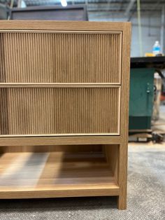 a wooden cabinet sitting on top of a floor next to a pile of wood planks