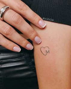 a woman's arm with a small heart tattoo on the left side of her stomach