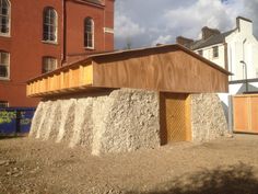 a wooden structure sitting on top of a pile of dirt next to a tall building