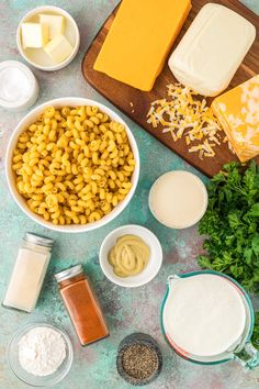 ingredients for macaroni salad laid out on a blue surface with cheese, parsley and butter