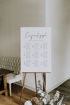 a seating chart is displayed on an easel next to a bench with flowers in it