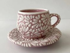 a pink cup and saucer sitting on top of a white tablecloth covered plate