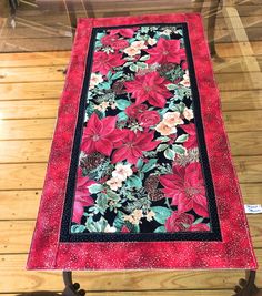 a red table runner with poinsettis on it