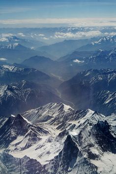 the view from an airplane looking down on snow covered mountains and valleys in the distance