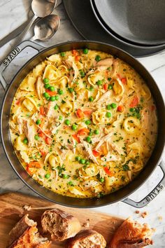 chicken noodle soup in a pan with bread on the side