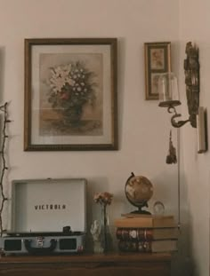 a room with pictures, flowers and an old record player on top of a dresser