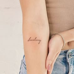 a woman's arm with the word daddy tattooed on her left side, in cursive font