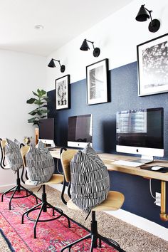 an office with zebra print chairs and computer screens on the wall, along with other desks