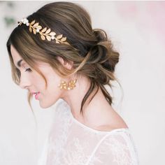 a woman wearing a gold leaf headpiece in front of a white wall with flowers on it