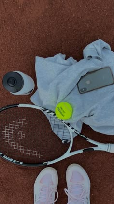 a tennis racket, cell phone and other items are laying on the ground next to each other