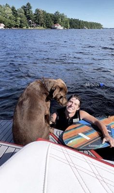 a woman and her dog on a boat in the water with their surfboards looking at each other