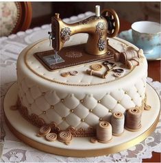 a white cake with gold trimmings and a sewing machine on top