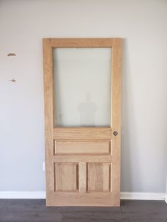 a wooden door with frosted glass on the top and bottom panel, in front of a white wall