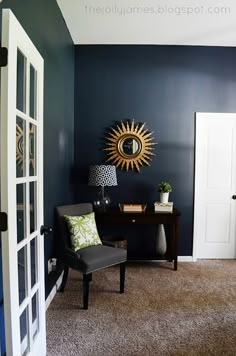 a living room with blue walls and a chair in front of the door that leads to another room